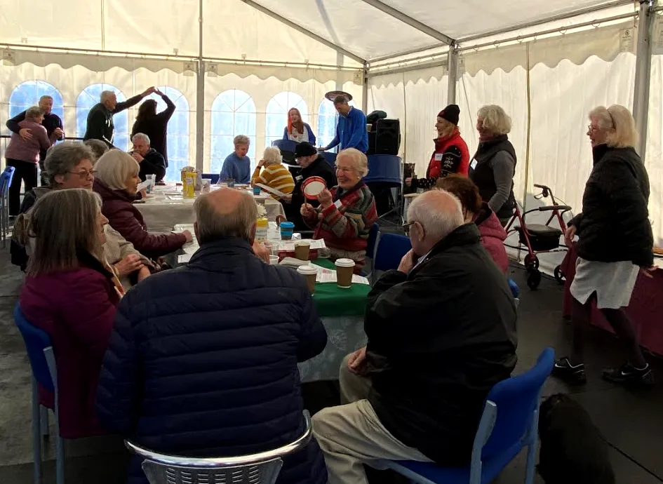 A group of people sat at tables in a marquee.