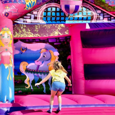 A young girl playing on a pink bouncy castle.